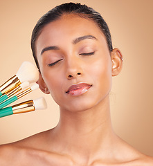 Image showing Makeup, beauty and brush with indian woman in studio for foundation, blush and self care. Glow, cosmetics and facial with female model isolated on brown background for shine, clean and confidence