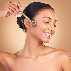 Image showing Woman, beauty and derma roller with face, happy with facial massage and skincare on studio background. Cosmetic tools, healthy skin glow and female smile with eyes closed, jade quartz and crystal