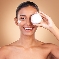 Image showing Indian woman, skincare cream and jar in portrait with smile, happiness and wellness by brown background. Happy model, lotion product and face in studio for dermatology, aesthetic and cosmetic beauty