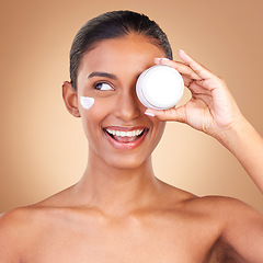 Image showing Indian woman, skincare cream and jar in studio with smile, happiness and wellness by brown background. Happy model, lotion product and face with thinking, dermatology and young with cosmetic beauty