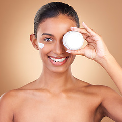 Image showing Indian woman, skin and cream jar in portrait with smile, happiness and wellness by brown background. Happy model, lotion product and skincare in studio for dermatology, healthy and cosmetic beauty