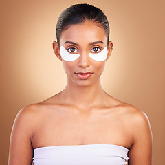 Image showing Skincare, eye patch and portrait of Indian woman in studio for facial, spa treatment and glow. Self care, cosmetics and hydration with female model on brown background for mask, product and youth