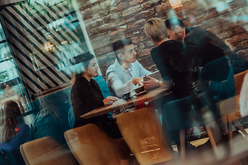 Image showing Happy businesspeople smiling cheerfully during a meeting in a coffee shop. Group of successful business professionals working as a team in a multicultural workplace.