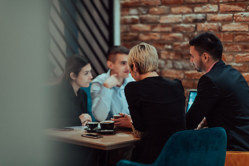 Image showing Happy businesspeople smiling cheerfully during a meeting in a coffee shop. Group of successful business professionals working as a team in a multicultural workplace.