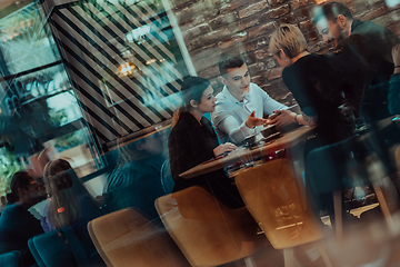 Image showing Happy businesspeople smiling cheerfully during a meeting in a coffee shop. Group of successful business professionals working as a team in a multicultural workplace.