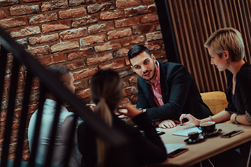 Image showing Happy businesspeople smiling cheerfully during a meeting in a coffee shop. Group of successful business professionals working as a team in a multicultural workplace.