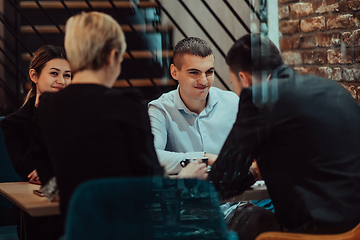 Image showing Happy businesspeople smiling cheerfully during a meeting in a coffee shop. Group of successful business professionals working as a team in a multicultural workplace.