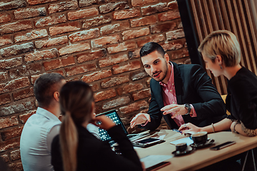 Image showing Happy businesspeople smiling cheerfully during a meeting in a coffee shop. Group of successful business professionals working as a team in a multicultural workplace.