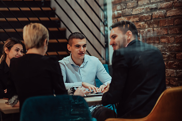 Image showing Happy businesspeople smiling cheerfully during a meeting in a coffee shop. Group of successful business professionals working as a team in a multicultural workplace.