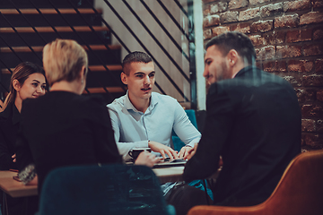 Image showing Happy businesspeople smiling cheerfully during a meeting in a coffee shop. Group of successful business professionals working as a team in a multicultural workplace.