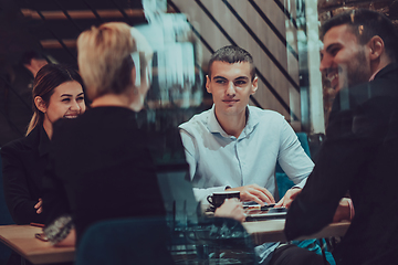 Image showing Happy businesspeople smiling cheerfully during a meeting in a coffee shop. Group of successful business professionals working as a team in a multicultural workplace.