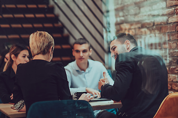 Image showing Happy businesspeople smiling cheerfully during a meeting in a coffee shop. Group of successful business professionals working as a team in a multicultural workplace.