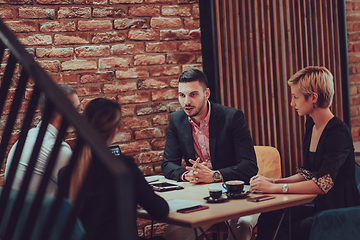 Image showing Happy businesspeople smiling cheerfully during a meeting in a coffee shop. Group of successful business professionals working as a team in a multicultural workplace.