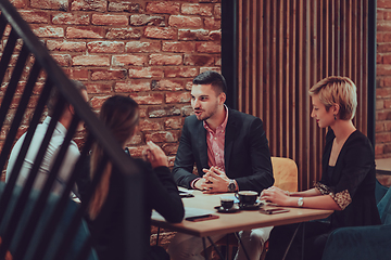 Image showing Happy businesspeople smiling cheerfully during a meeting in a coffee shop. Group of successful business professionals working as a team in a multicultural workplace.