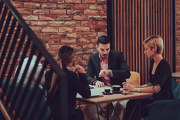 Image showing Happy businesspeople smiling cheerfully during a meeting in a coffee shop. Group of successful business professionals working as a team in a multicultural workplace.