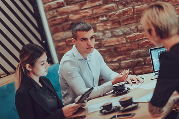 Image showing Happy businesspeople smiling cheerfully during a meeting in a coffee shop. Group of successful business professionals working as a team in a multicultural workplace.