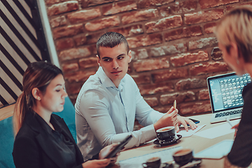 Image showing Happy businesspeople smiling cheerfully during a meeting in a coffee shop. Group of successful business professionals working as a team in a multicultural workplace.