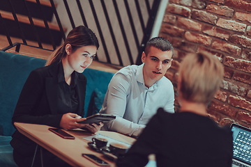 Image showing Happy businesspeople smiling cheerfully during a meeting in a coffee shop. Group of successful business professionals working as a team in a multicultural workplace.