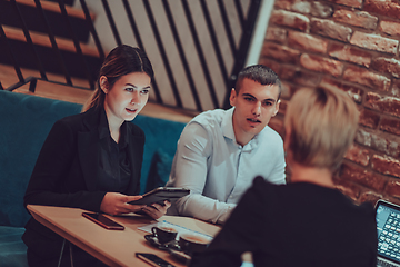 Image showing Happy businesspeople smiling cheerfully during a meeting in a coffee shop. Group of successful business professionals working as a team in a multicultural workplace.