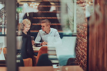 Image showing Photo through the glass of a group of business people sitting in a cafe and discussing business plans and ideas for new online commercial services