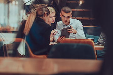 Image showing Photo through the glass of a group of business people sitting in a cafe and discussing business plans and ideas for new online commercial services