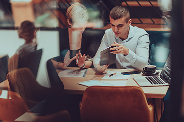 Image showing Photo through the glass of a group of business people sitting in a cafe and discussing business plans and ideas for new online commercial services