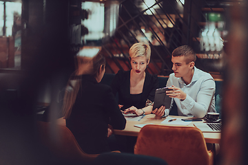 Image showing Photo through the glass of a group of business people sitting in a cafe and discussing business plans and ideas for new online commercial services