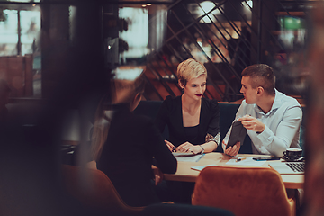 Image showing Photo through the glass of a group of business people sitting in a cafe and discussing business plans and ideas for new online commercial services