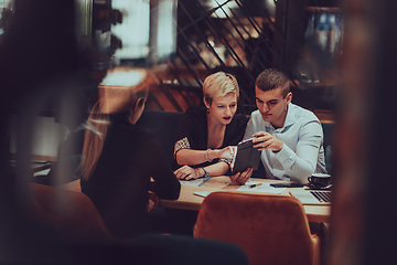 Image showing Photo through the glass of a group of business people sitting in a cafe and discussing business plans and ideas for new online commercial services