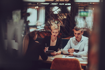 Image showing Photo through the glass of a group of business people sitting in a cafe and discussing business plans and ideas for new online commercial services