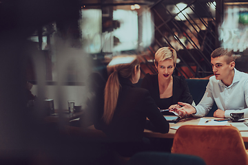 Image showing Photo through the glass of a group of business people sitting in a cafe and discussing business plans and ideas for new online commercial services