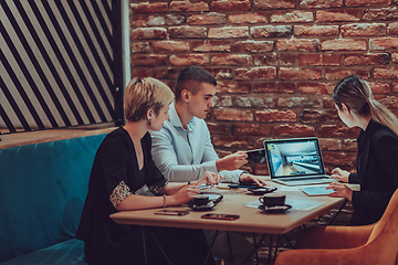 Image showing Happy businesspeople smiling cheerfully during a meeting in a coffee shop. Group of successful business professionals working as a team in a multicultural workplace.