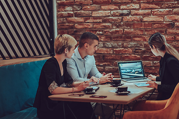 Image showing Happy businesspeople smiling cheerfully during a meeting in a coffee shop. Group of successful business professionals working as a team in a multicultural workplace.