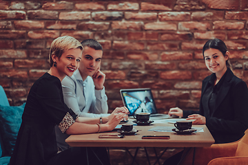 Image showing Happy businesspeople smiling cheerfully during a meeting in a coffee shop. Group of successful business professionals working as a team in a multicultural workplace.