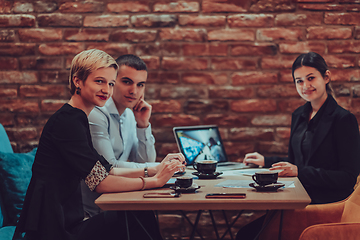 Image showing Happy businesspeople smiling cheerfully during a meeting in a coffee shop. Group of successful business professionals working as a team in a multicultural workplace.