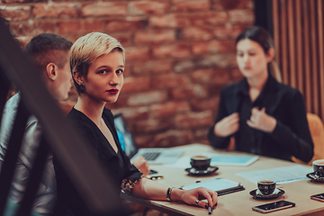 Image showing Happy businesspeople smiling cheerfully during a meeting in a coffee shop. Group of successful business professionals working as a team in a multicultural workplace.