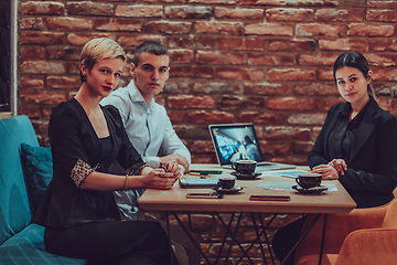 Image showing Happy businesspeople smiling cheerfully during a meeting in a coffee shop. Group of successful business professionals working as a team in a multicultural workplace.