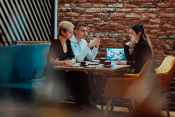 Image showing Happy businesspeople smiling cheerfully during a meeting in a coffee shop. Group of successful business professionals working as a team in a multicultural workplace.