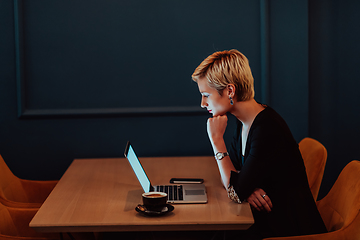 Image showing Businesswoman sitting in a cafe while focused on working on a laptop and participating in an online meetings. Selective focus.