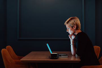 Image showing Businesswoman sitting in a cafe while focused on working on a laptop and participating in an online meetings. Selective focus.