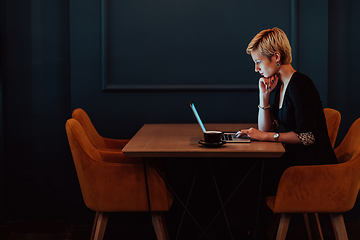 Image showing Businesswoman sitting in a cafe while focused on working on a laptop and participating in an online meetings. Selective focus.