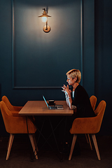 Image showing Businesswoman sitting in a cafe while focused on working on a laptop and participating in an online meetings. Selective focus.