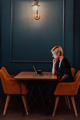 Image showing Businesswoman sitting in a cafe while focused on working on a laptop and participating in an online meetings. Selective focus.