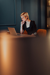 Image showing Businesswoman sitting in a cafe while focused on working on a laptop and participating in an online meetings. Selective focus.