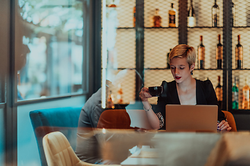 Image showing Businesswoman sitting in a cafe while focused on working on a laptop and participating in an online meetings. Selective focus.