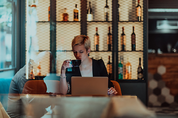 Image showing Businesswoman sitting in a cafe while focused on working on a laptop and participating in an online meetings. Selective focus.