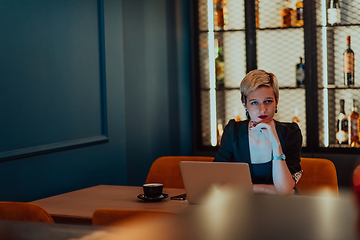 Image showing Businesswoman sitting in a cafe while focused on working on a laptop and participating in an online meetings. Selective focus.