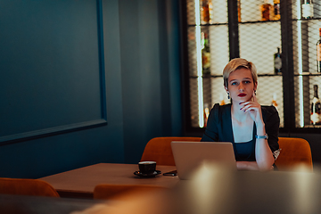 Image showing Businesswoman sitting in a cafe while focused on working on a laptop and participating in an online meetings. Selective focus.