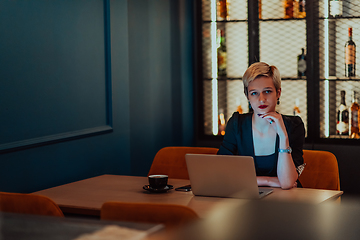 Image showing Businesswoman sitting in a cafe while focused on working on a laptop and participating in an online meetings. Selective focus.