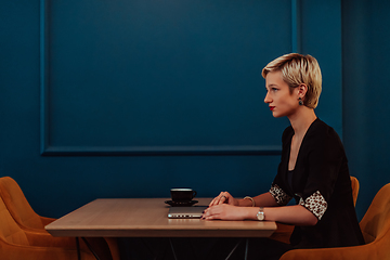 Image showing Businesswoman sitting in a cafe while focused on working on a laptop and participating in an online meetings. Selective focus.